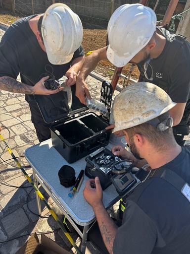 Equipe técnica realizando fusão de fibra óptica em campo